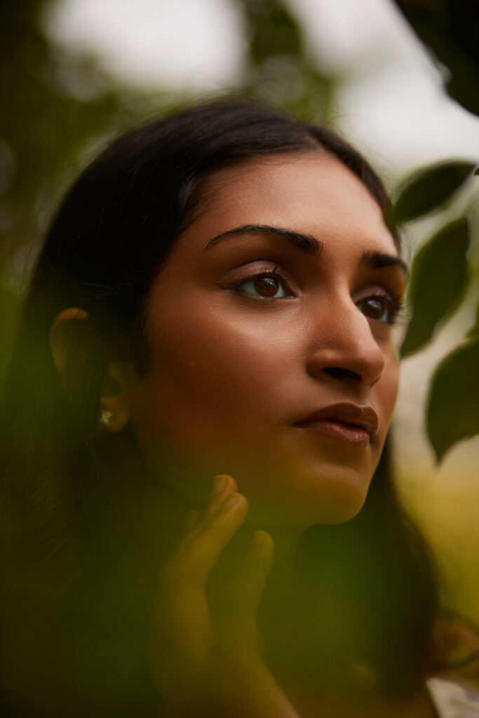 Portrait of woman framed by green leaves, natural light portrait photography by Motor City Moda
