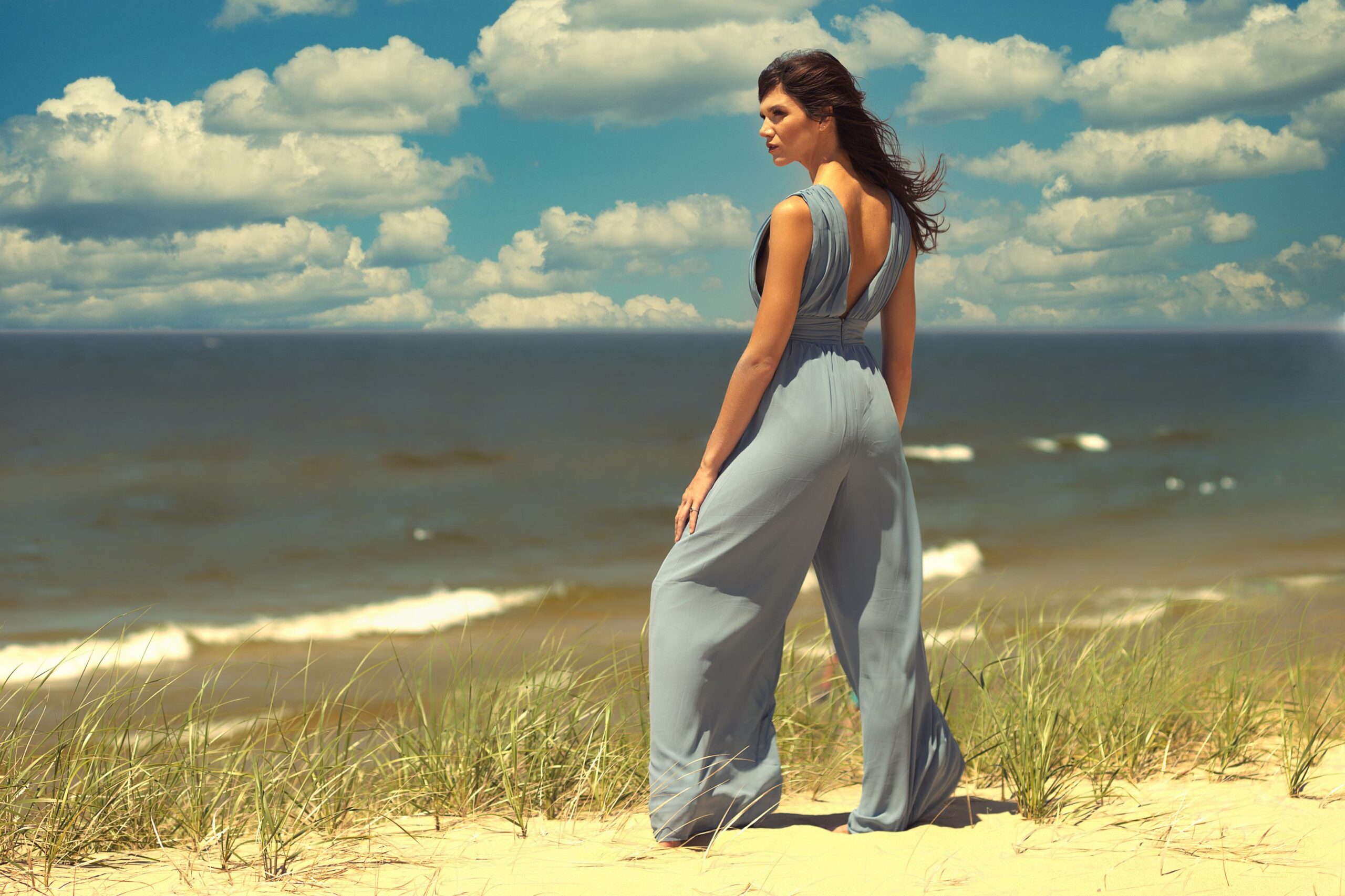 Fashion portrait of woman in blue wide-leg jumpsuit looking out over Lake Michigan shoreline at Hoffmaster State Park Muskegon Michigan