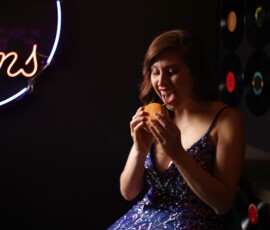 Playful Retro Diner Fashion Portrait — Grand Rapids Michigan Playful fashion portrait of woman in blue sequin gown laughing while eating burger at retro diner with neon sign Grand Rapids Michigan