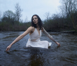 Editorial Outdoor Fashion Photography — Detroit Metro Michigan River Session Editorial outdoor fashion portrait woman wet white boho dress rose tattoo sleeve sitting river arm extended direct gaze Detroit Metro Michigan