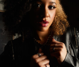 Traverse City Michigan Close Up Fashion Photography — Leather and Gold Close up fashion portrait of woman with curly hair in black leather jacket holding lapels with gold chain necklace and rings Traverse City Michigan