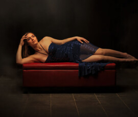 Cinematic Studio Fashion Photography — Oakland County Michigan Cinematic studio fashion portrait of woman in navy sequin halter dress reclining on red ottoman dramatic dark background Oakland County Michigan