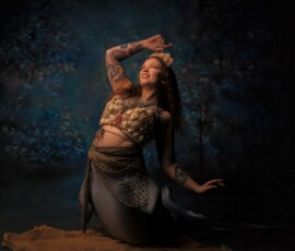 Metro Detroit Creative Mermaid Fashion Photography — Oakland County Michigan Creative mermaid concept fashion portrait of tattooed woman in shell crown arm raised smiling against blue underwater backdrop Oakland County Michigan