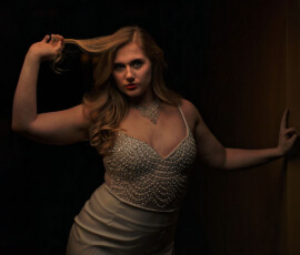 Oakland County Michigan Moody Studio Fashion Photography Moody studio fashion portrait of woman in crystal embellished dress and diamond necklace leaning against dark wall Oakland County Michigan