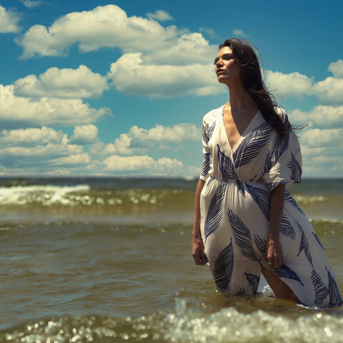 Lake Michigan Fashion Session — West Michigan Fashion portrait of a woman standing in Lake Michigan waves wearing a white and blue leaf print maxi dress, west Michigan shoreline photography