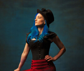 Creative Steampunk Studio Portrait — Oakland County Michigan Photographer Dramatic profile steampunk concept fashion portrait of woman with blue hair black corset red skirt top hat looking away Oakland County Michigan